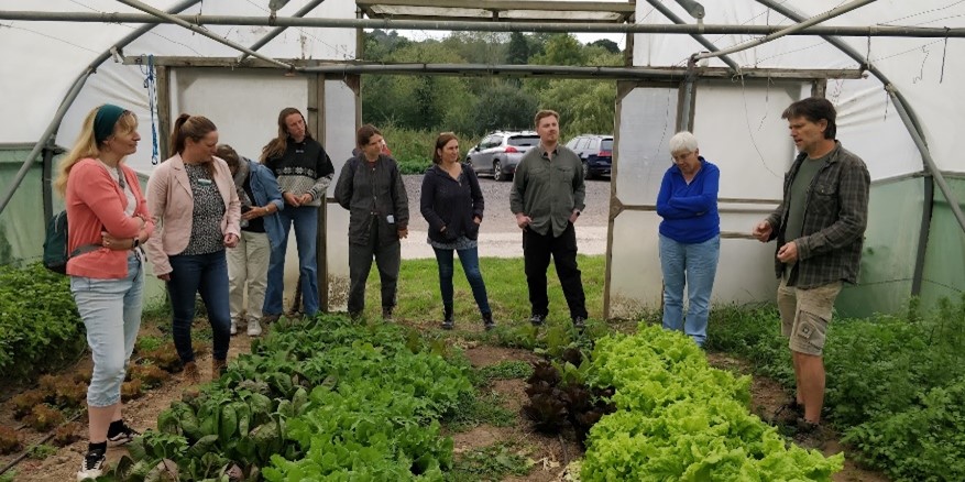Group of people attending a tour of Tablehurst Farm. Picture shows the group receiving a talk in a polytunnel.
